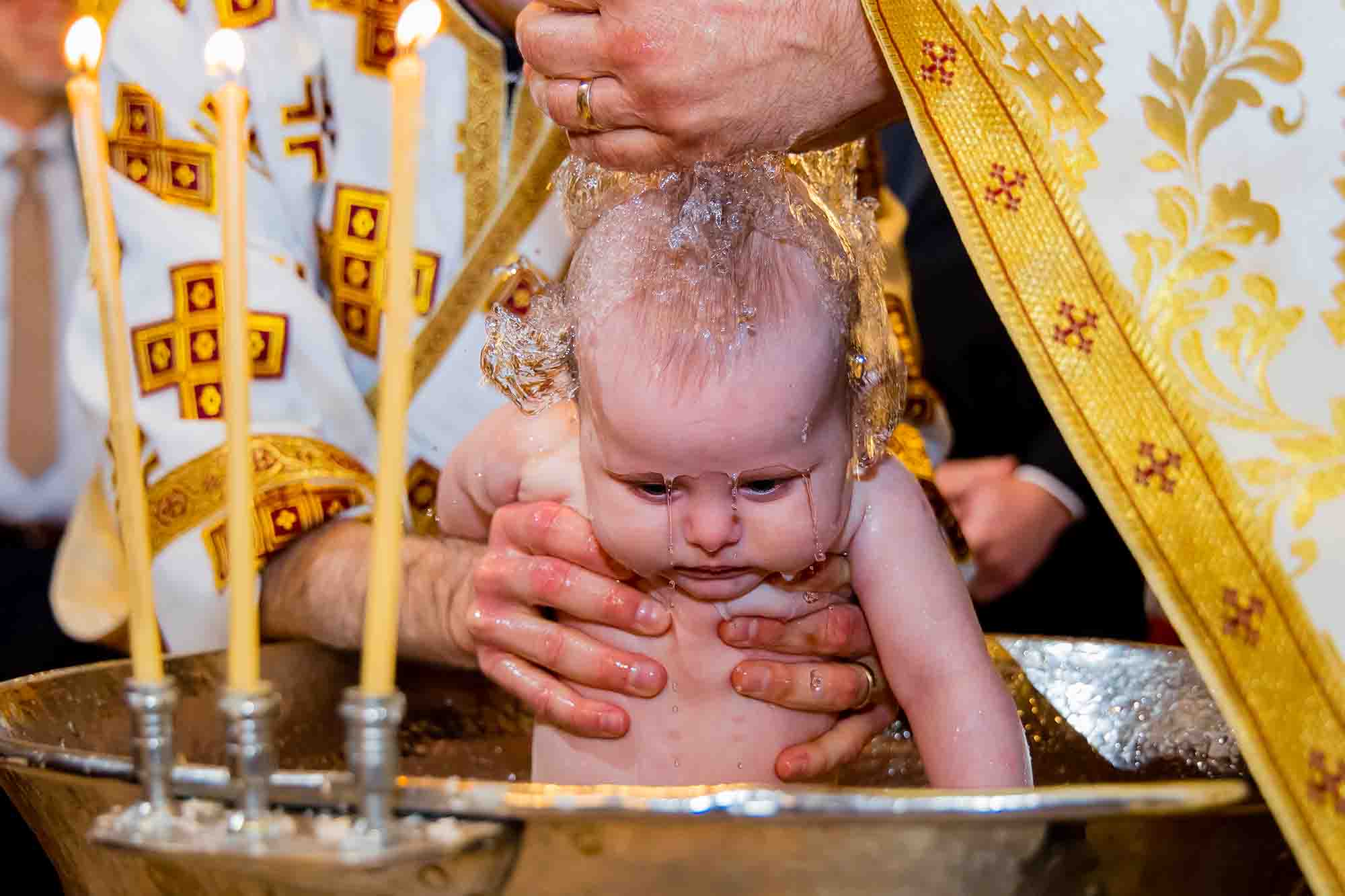 copil stropit cu apa la botez